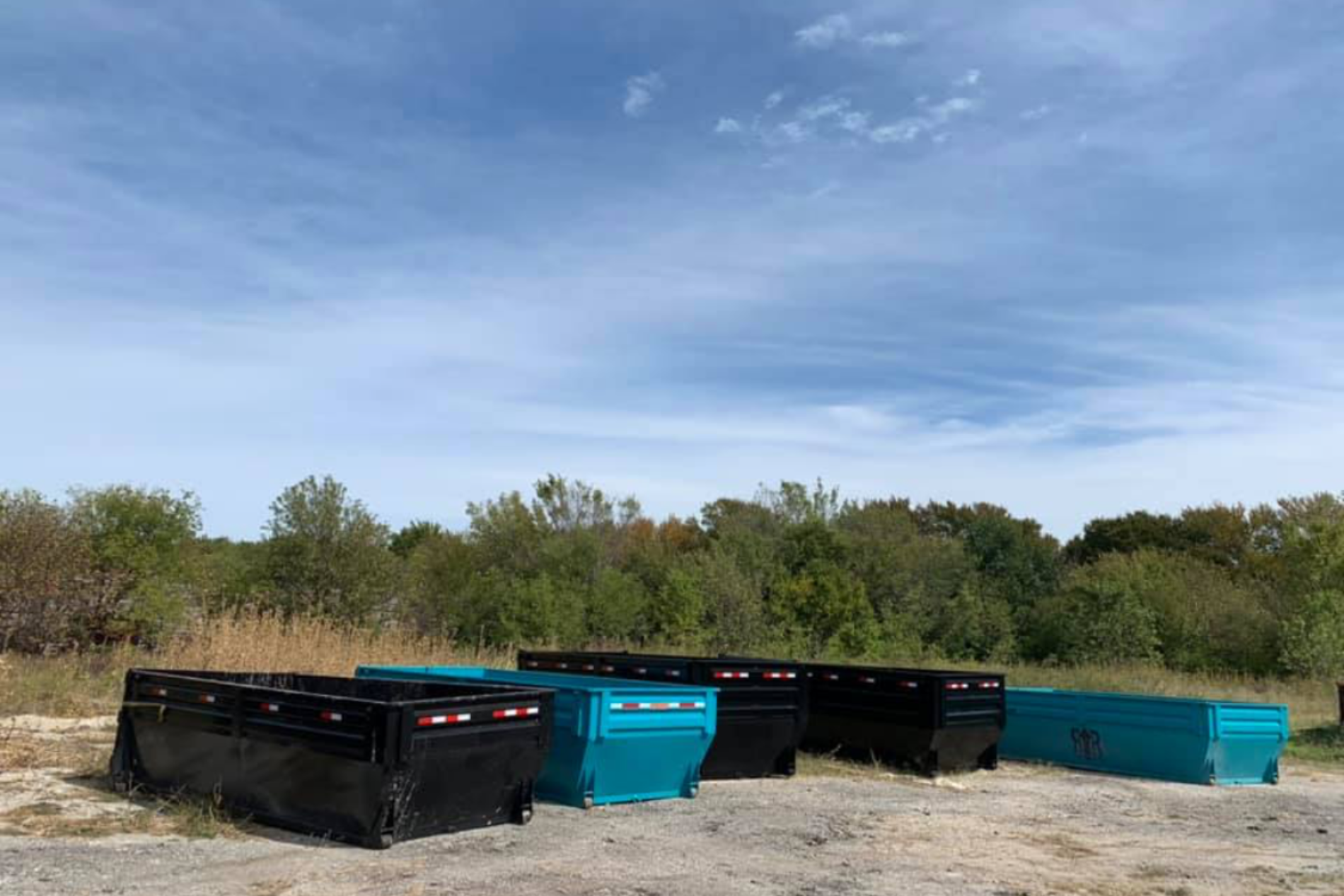 Blue and black dumpsters in an empty field